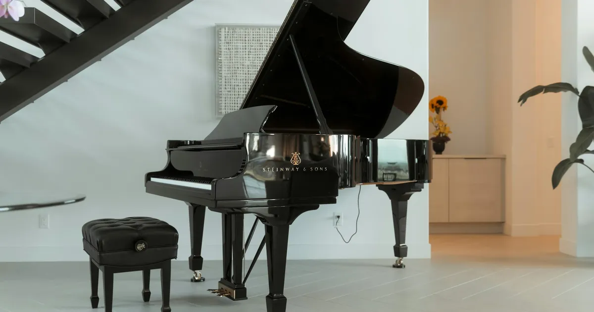 Black grand piano in a bright living room next to a staircase