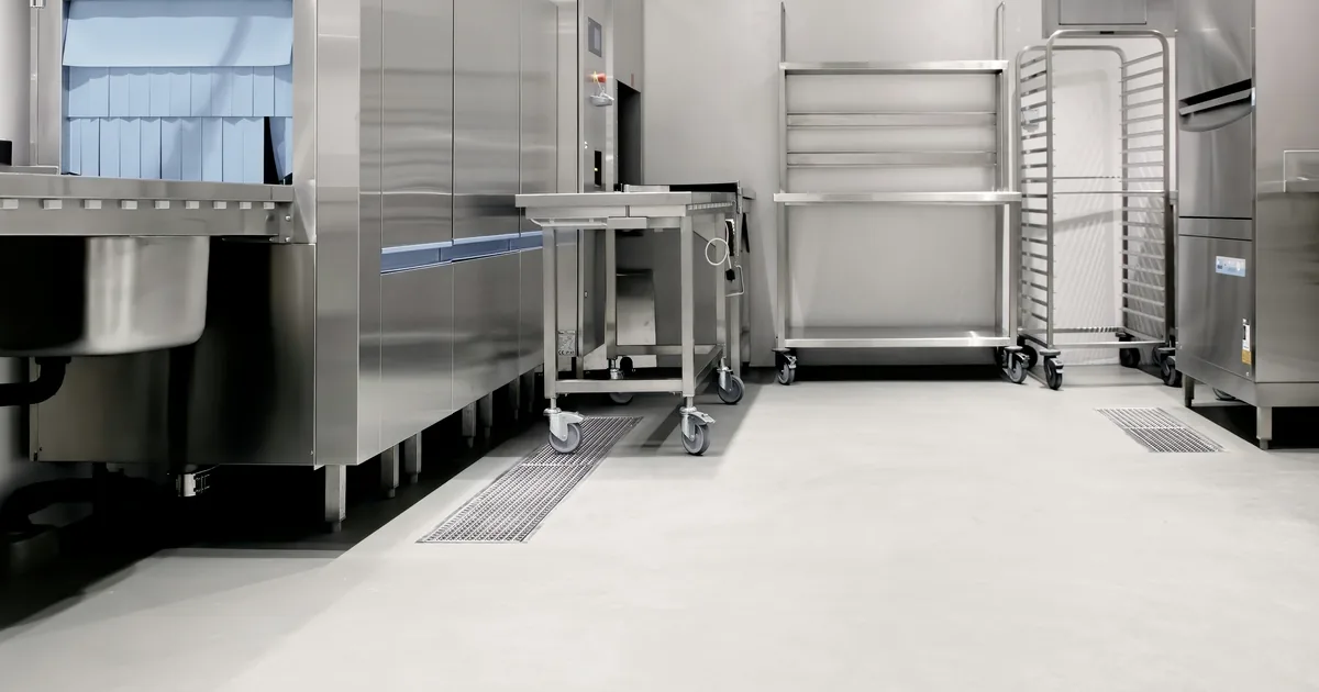 Empty commercial kitchen with a stainless steel dish station, prep table and rolling racks