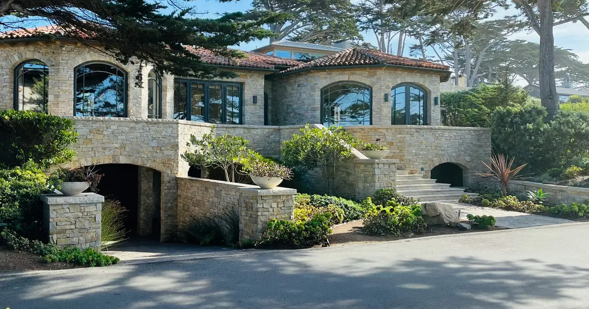 Large two-story house behind mature trees in Carmel-by-the-Sea, California
