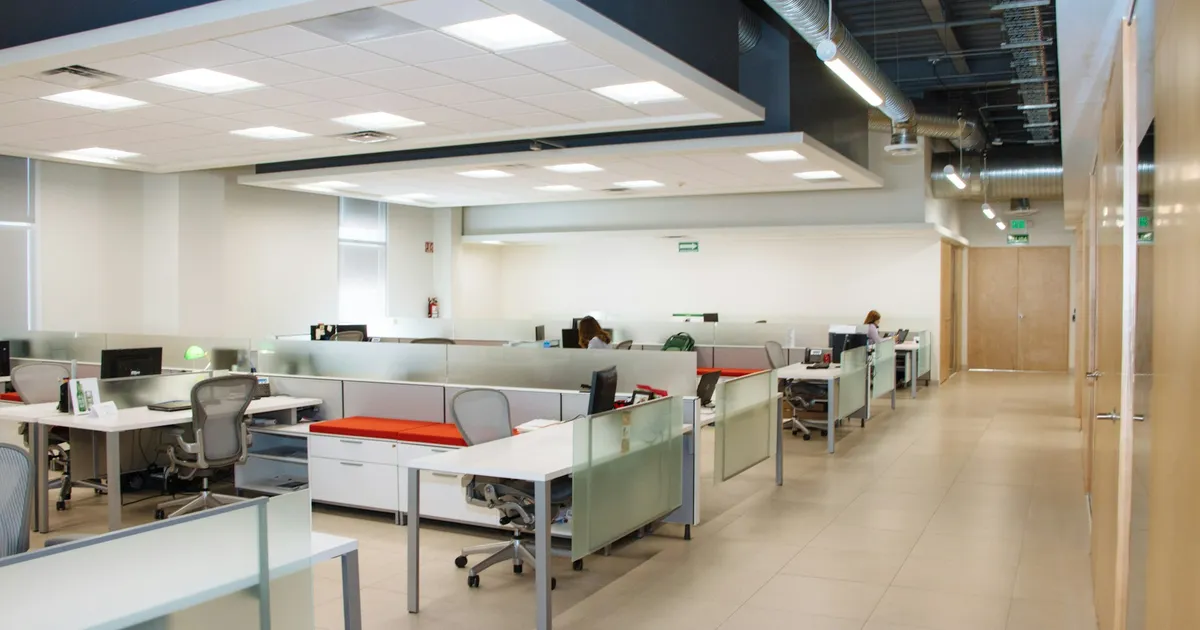 Bright open-plan office with rows of white desks and chairs