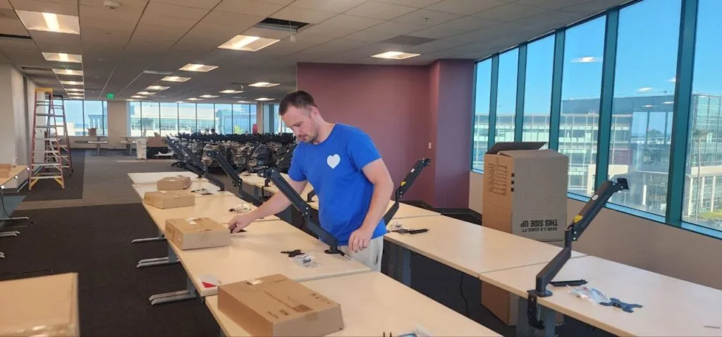 Impel mover installing monitor arms on office desks during a workplace move